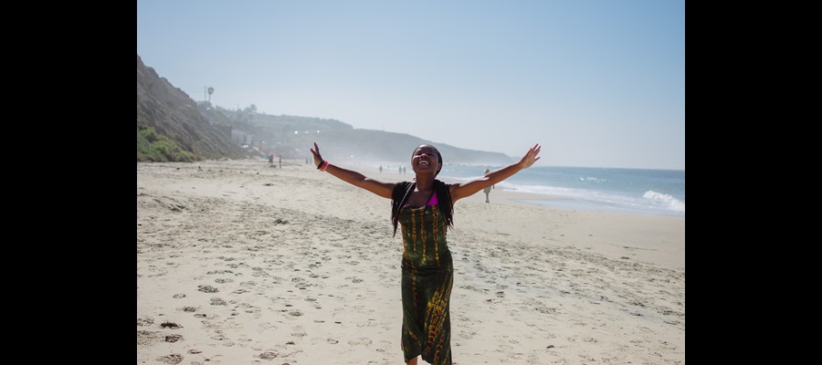 DiLA Student posing arms in the air on the beach SU2023 CR:TessaMartinko
